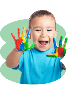 INiño en etapa de educación inicial mostrando sus manos pintadas de colores durante una actividad de aprendizaje creativo.